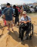 คนพิการนั่งรถเข็นทดลองเข็นรถเข็นไปบริเวณชายหาด