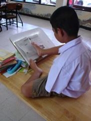 นักเรียนชายพิการแขนขาดสองข้าง กำลังนั่งอ่านหนังสือ