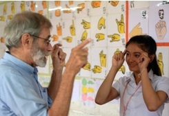 ชา ร์ลี ดิตต์มายเออร์ (ซ้าย) ใช้ภาษามือสื่อสารกับนักเรียนหูหนวกชาวกัมพูชา ในห้องเรียน ในกรุงพนมเปญ.--Agence France-Presse/Tang Chhin Sothy.