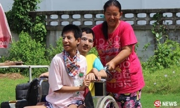 นางบงกช จันทร์สนิท อายุ 45 ปี กำลังเข็นรถให้ลูกชายพิการทั้งสองคน