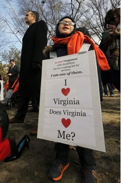 Joe Tremblay, 8, from Colonial Heights, wears a sign in support of Virginians with disabilities as Virginia Lt. Gov. Ralph Northam, left, waits to speak at a rally held at the Bell Tower on Capitol Square in Richmond Tuesday.