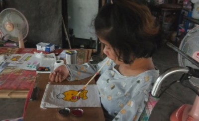 วอนช่วยสาวพิการ สู้ชีวิตใช้ปากคาบพู่กันเพ้นท์กระเป๋าผ้าขายเลี้ยงชีพ