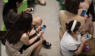 ภาพ คนนั่งเล่นโทรศัพท์มือถือสมาร์ทโฟน