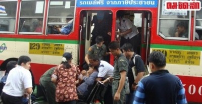 คนพิการนั่งรถเข็นกำลังขึ้นบรรไดของรถเมล์แบบทั่วไปโดยมีคนมาช่วยยกรถขึ้นอย่างลำบาก