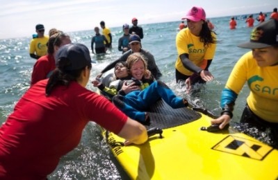 Volunteers help four-year-old Divya Tiwari, who is dependent on a wheelchair, experience the sensation of surfing. (Darren Calabrese/Canadian Press)